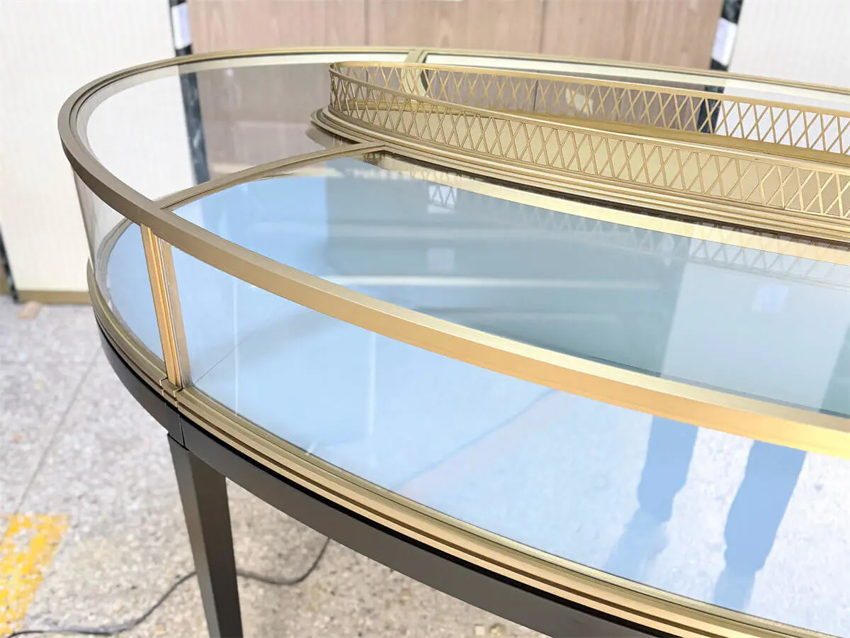 Close-up of stainless steel craftsmanship on Luxury Oval Island Jewelry Showcase with elegant brushed brass finish